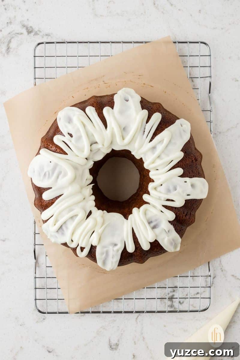 Baked bundt cake with frosting on top of a cooling rack.