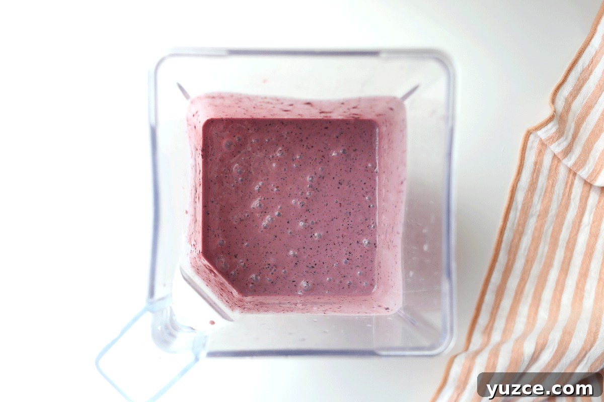Blueberry Spinach Smoothie Recipe for Energy and Weight Support 5 A blender with a blended spinach and blueberry smoothie in it.