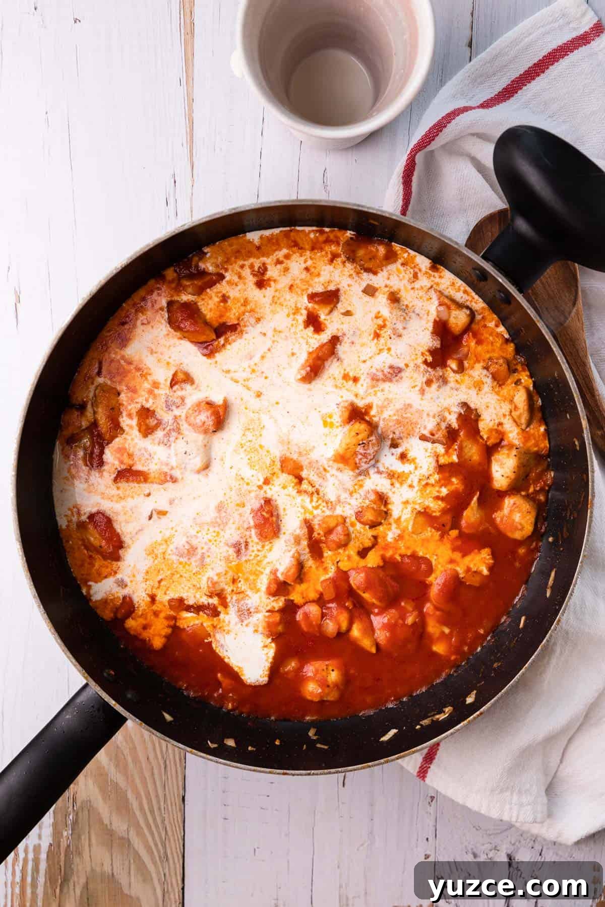 a skillet with chicken, tomato sauce and cream