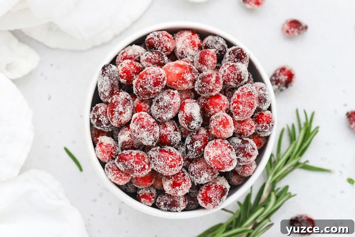 Sugared Cranberries Recipe: Simple Steps for Sparkling Cranberry Garnish 21 Overhead view of a bowl of sugared cranberries with a sprig of rosemary in the background