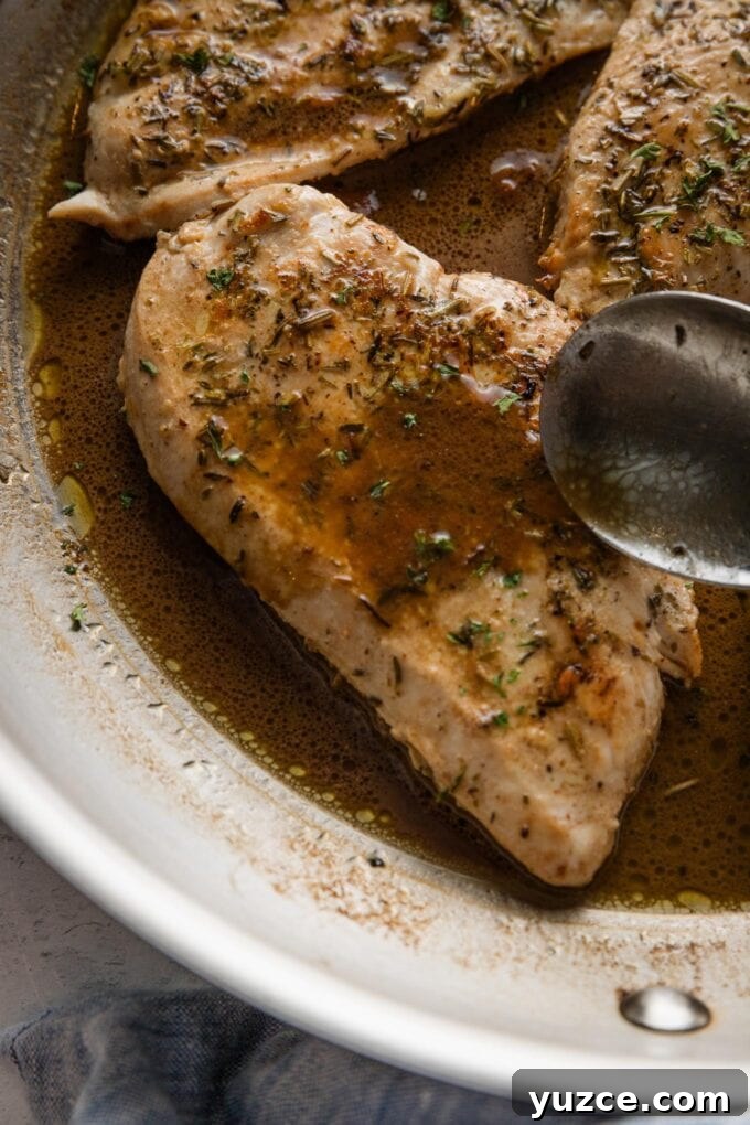Balsamic Pan-Seared Chicken Breasts with Garlic and Herbs 6 Close up of a spoon drizzling sauce over a chicken breast.