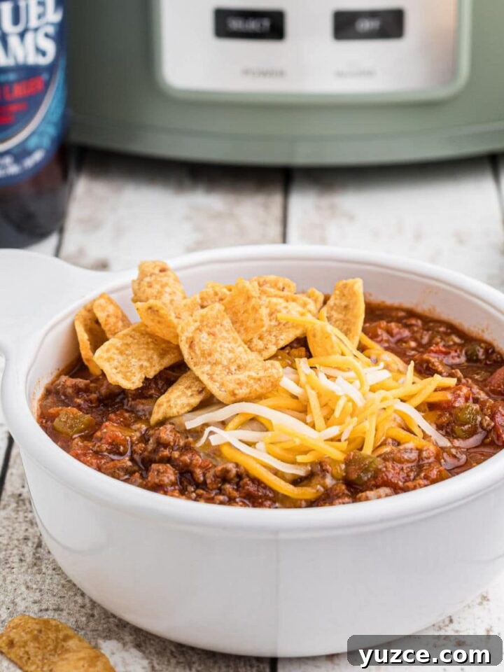 Hearty Dutch Oven Soup Recipes for Cozy Meals 19 Close up side view of a bowl of beer chili with a crock pot in the background.