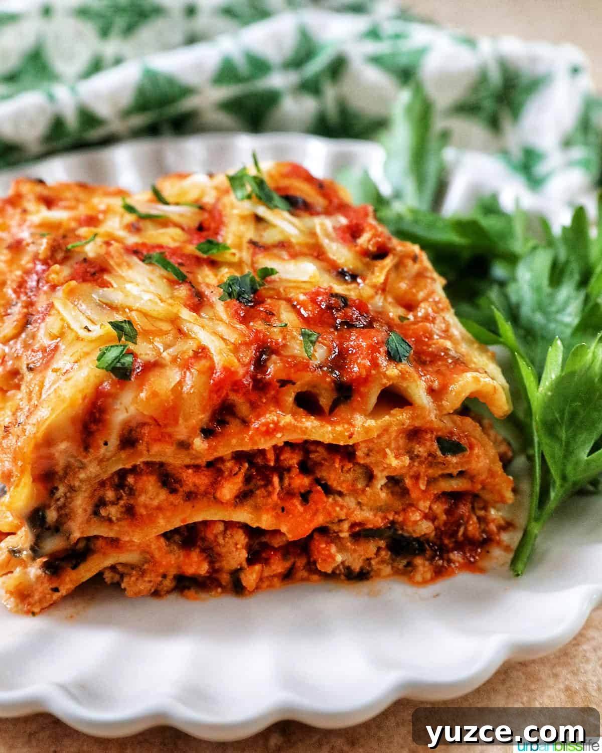 Perfect Wine Pairings for Popular Pasta Dishes 5 side view of multi-layered dairy free lasagna on a white plate with green and white napkin in background.
