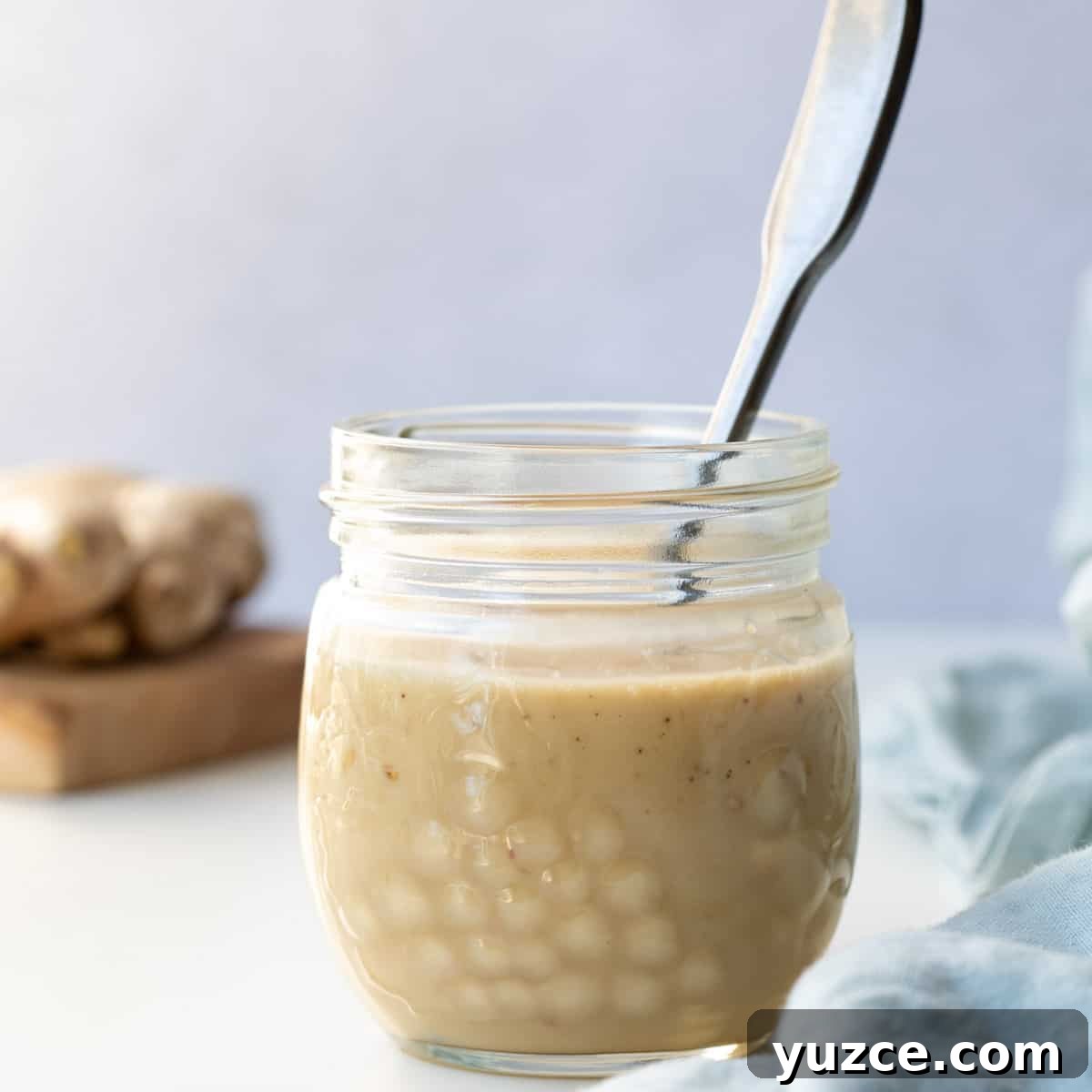 close up of jar of sesame ginger dressing in front of cutting board with ginger