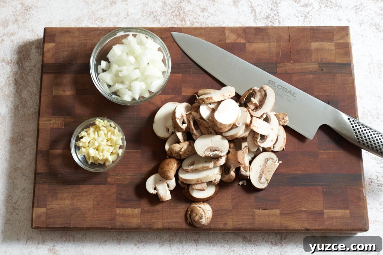 Slow Cooker Chicken Cacciatore Recipe for Tender, Flavorful Meals 5 A knife on a cutting board with sliced mushrooms and two small bowls of diced onions and garlic.