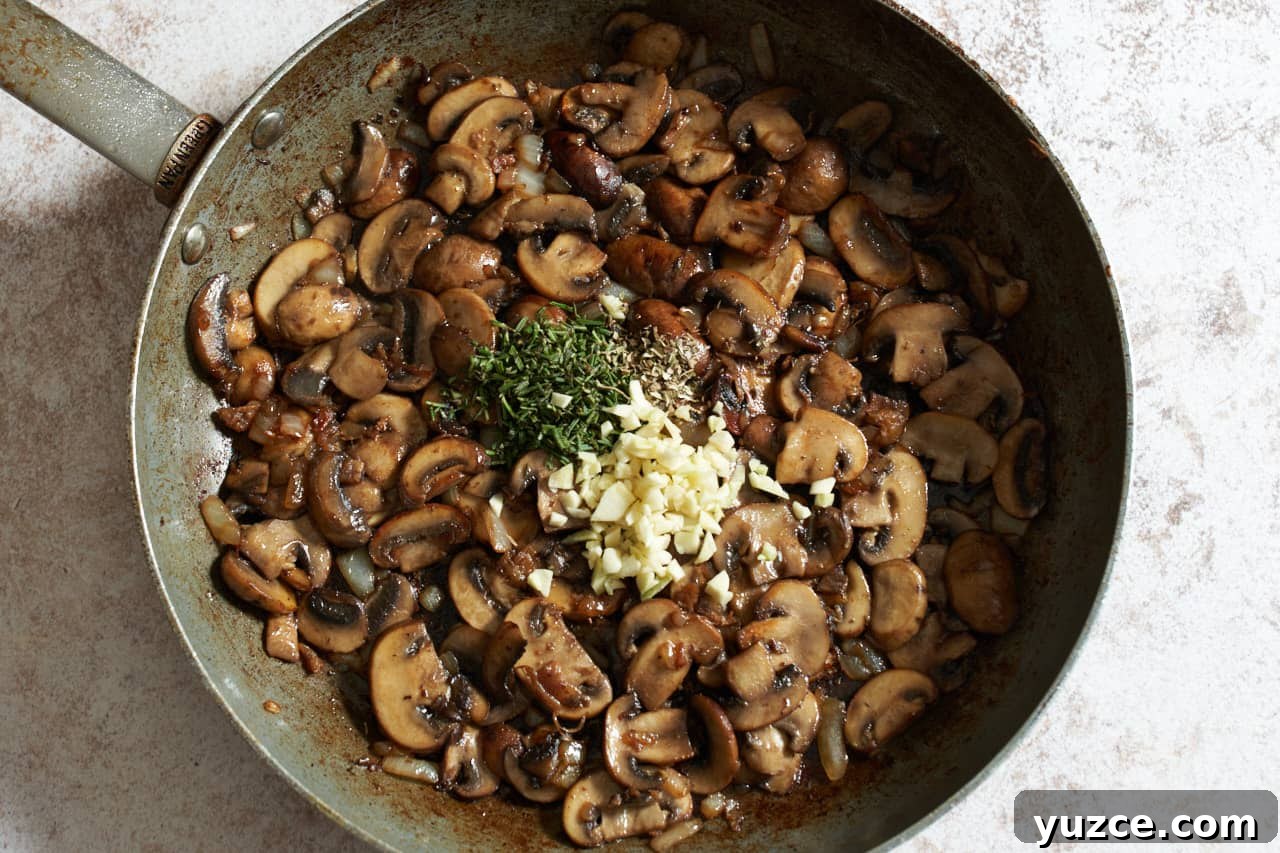 Slow Cooker Chicken Cacciatore Recipe for Tender, Flavorful Meals 6 Cooked mushrooms in a skillet with diced garlic and chopped rosemary added.