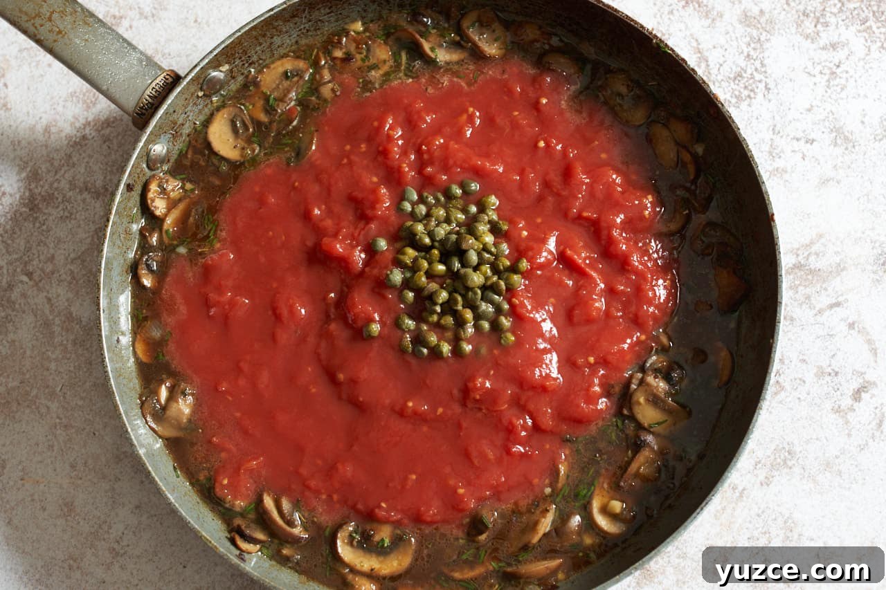 Slow Cooker Chicken Cacciatore Recipe for Tender, Flavorful Meals 8 Tomatos and capers being added to a skillet of mushrooms and broth.