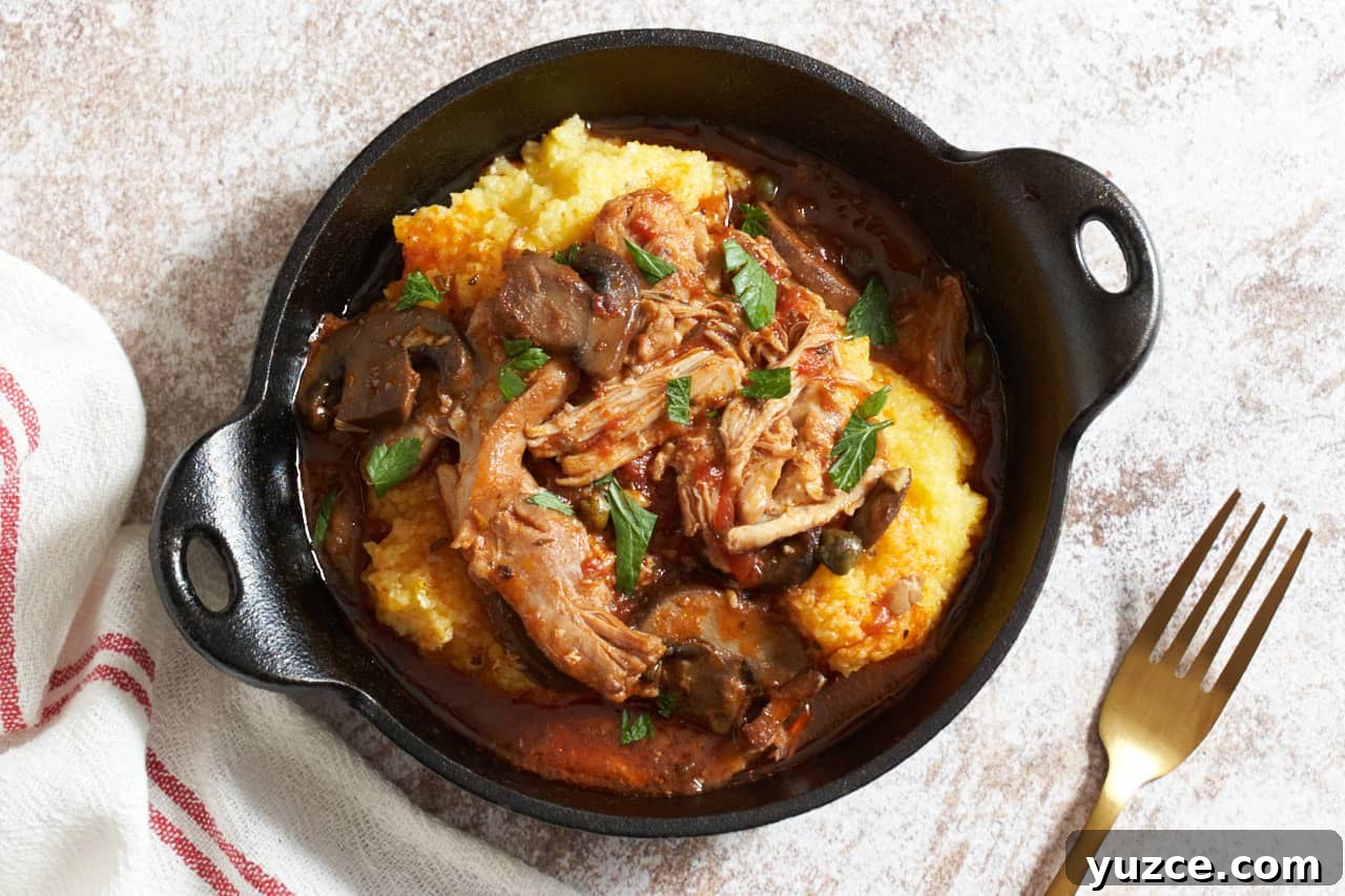 Slow Cooker Chicken Cacciatore Recipe for Tender, Flavorful Meals 10 A cast iron serving dish of slow cooker chicken cacciatore over polenta. A gold forks is on the right, a red and white striped towel is on the left.