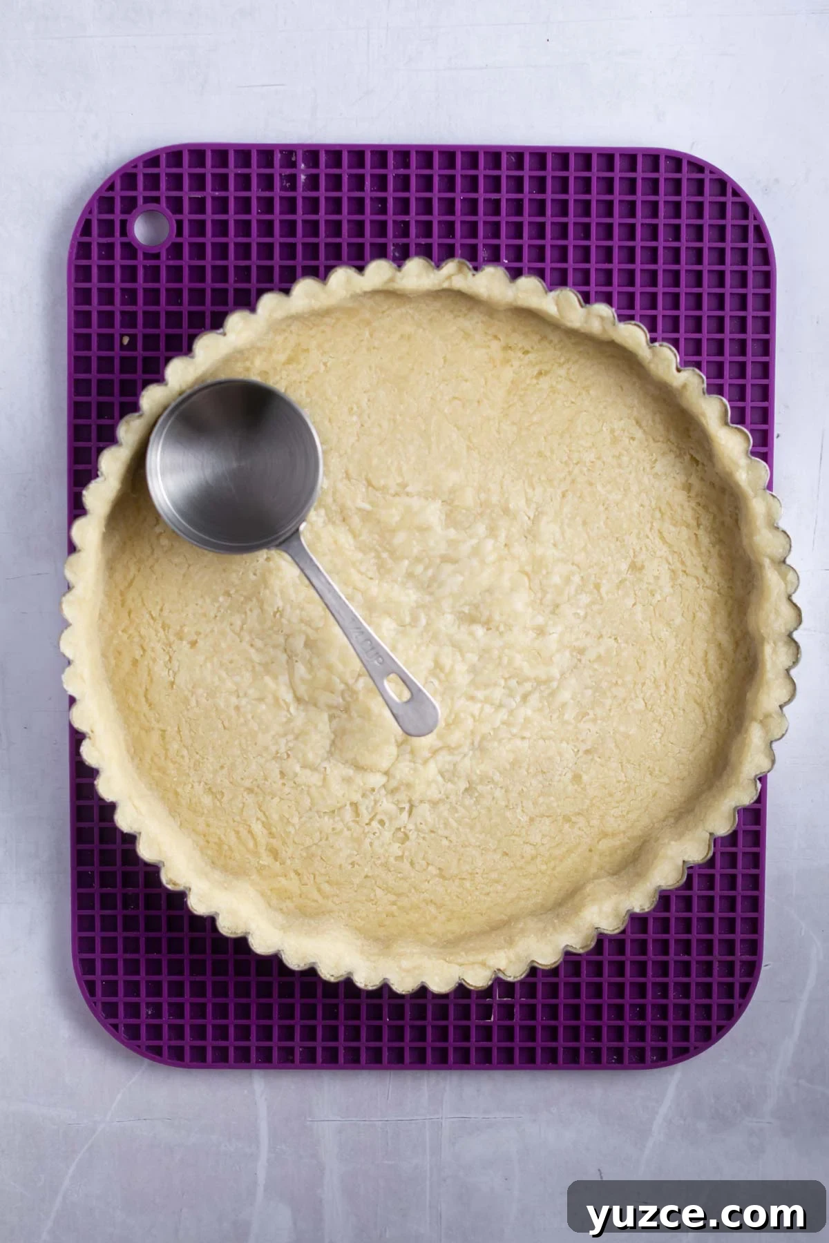 Lemon Raspberry Tart Recipe with a Buttery Shortcrust 10 par baked shortbread crust with a measuring cup showing how to flatten the bottom